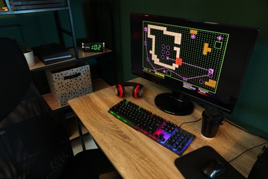 Modern computer, RGB keyboard and headphones on wooden table indoors