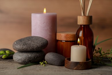 Photo of Beautiful spa composition with different care products and burning candles on wooden table, closeup