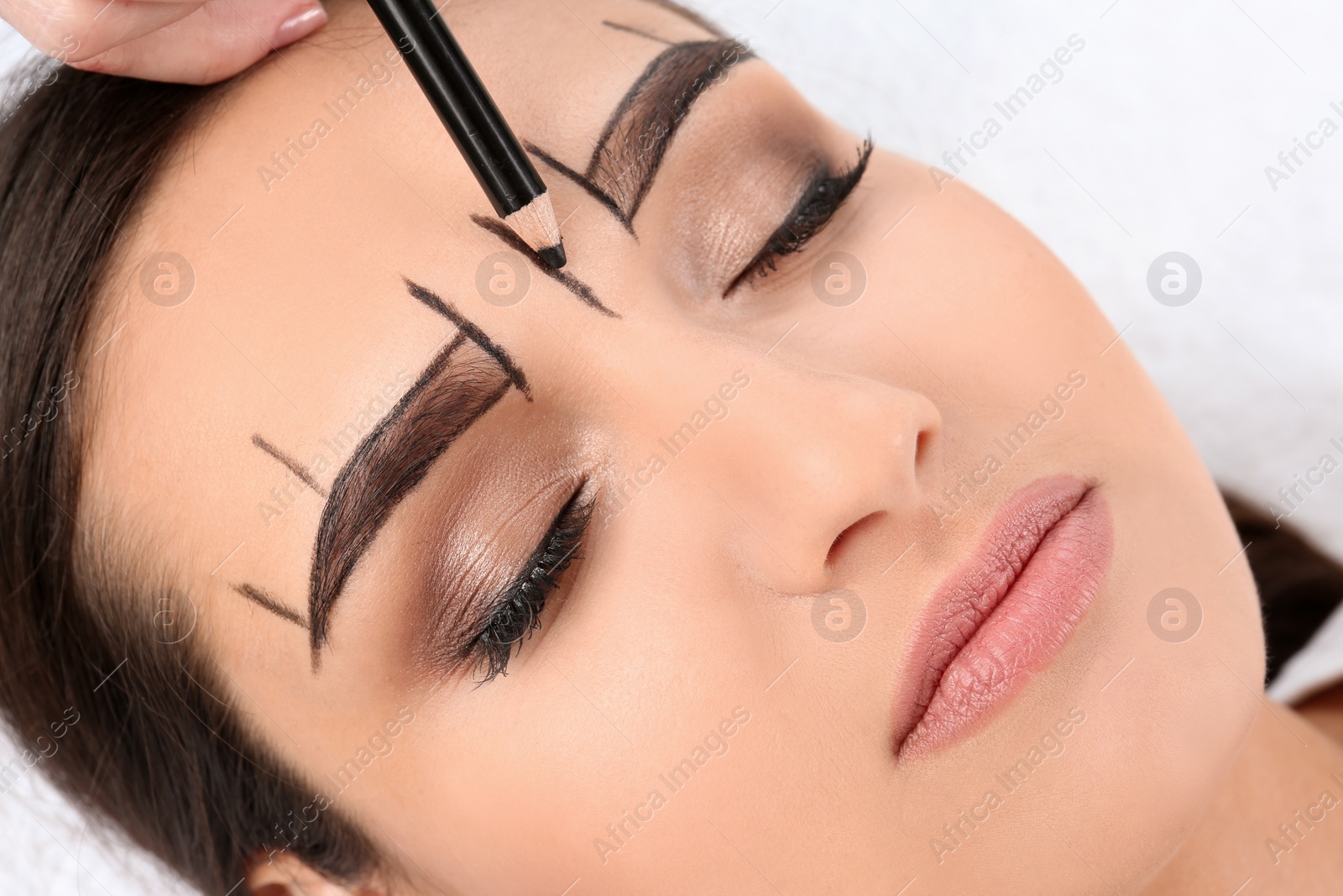 Photo of Cosmetologist preparing young woman for  eyebrow permanent makeup procedure, closeup