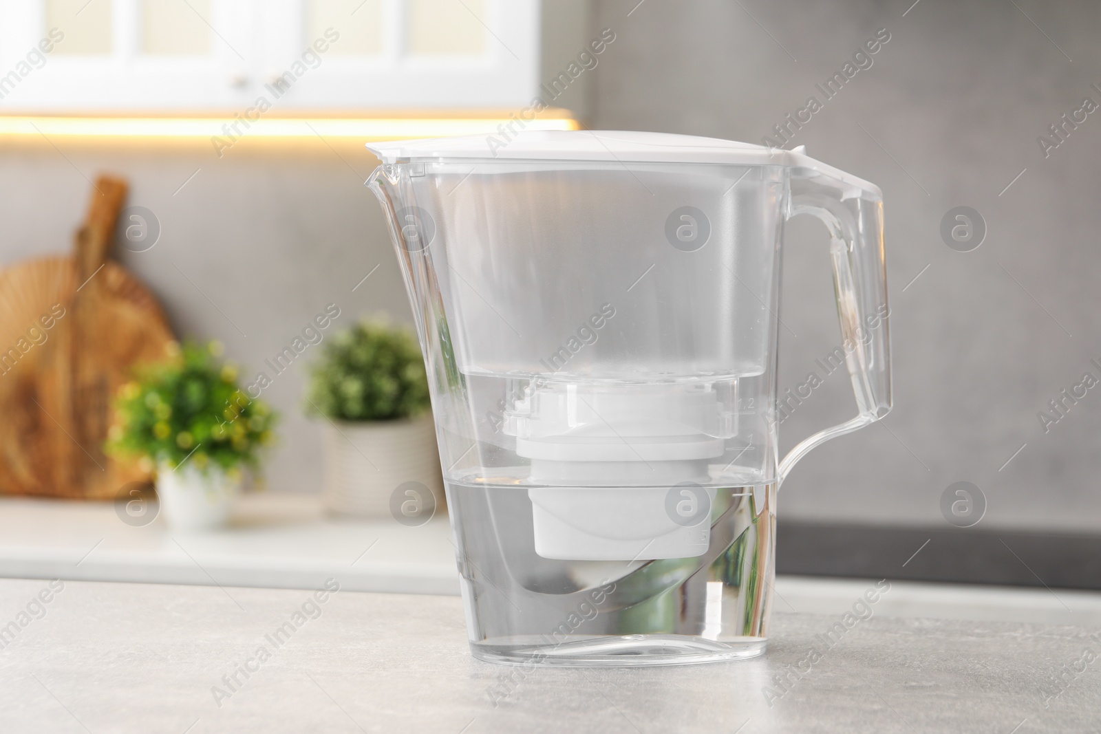 Photo of Water filter jug on light grey table in kitchen, space for text