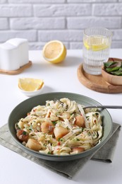 Delicious scallop pasta with spices in bowl served on white table