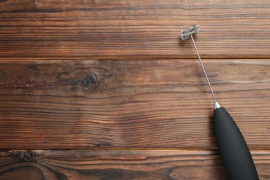 Black milk frother wand on wooden table, top view. Space for text