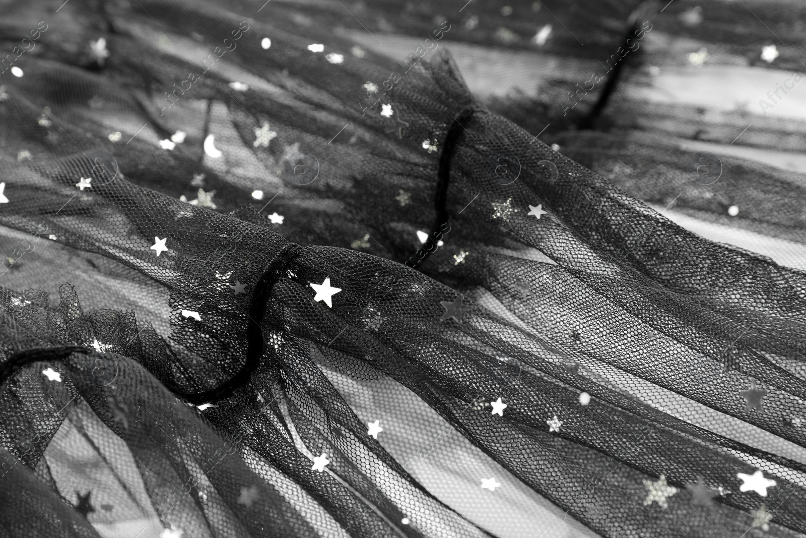 Photo of Beautiful black tulle fabric with shiny stars as background, closeup