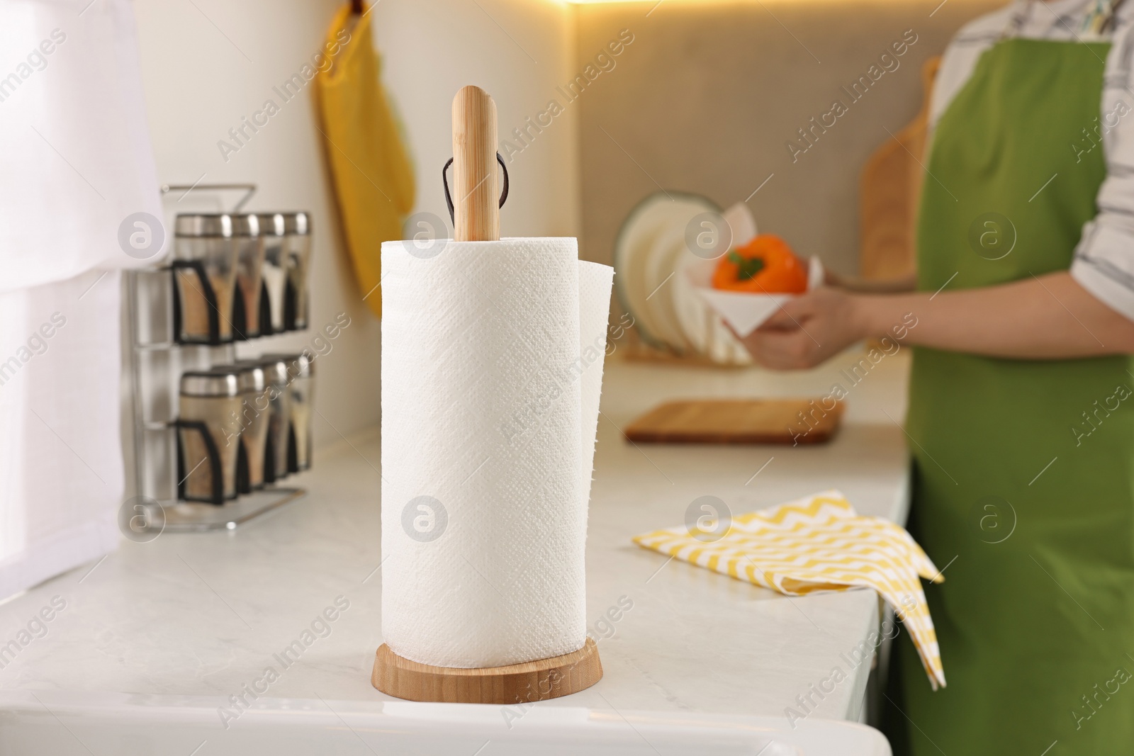 Photo of Roll of paper towels in kitchen and woman wiping bell pepper on background. Space for text