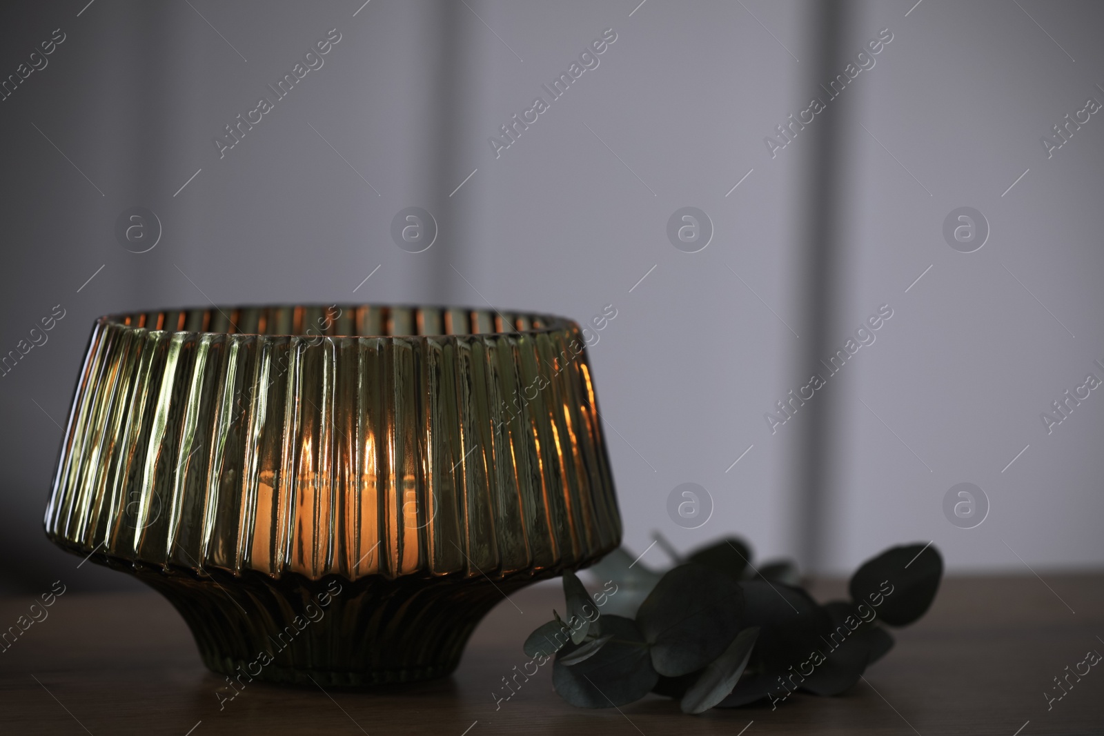 Photo of Stylish lantern with burning candle on wooden table indoors. Space for text