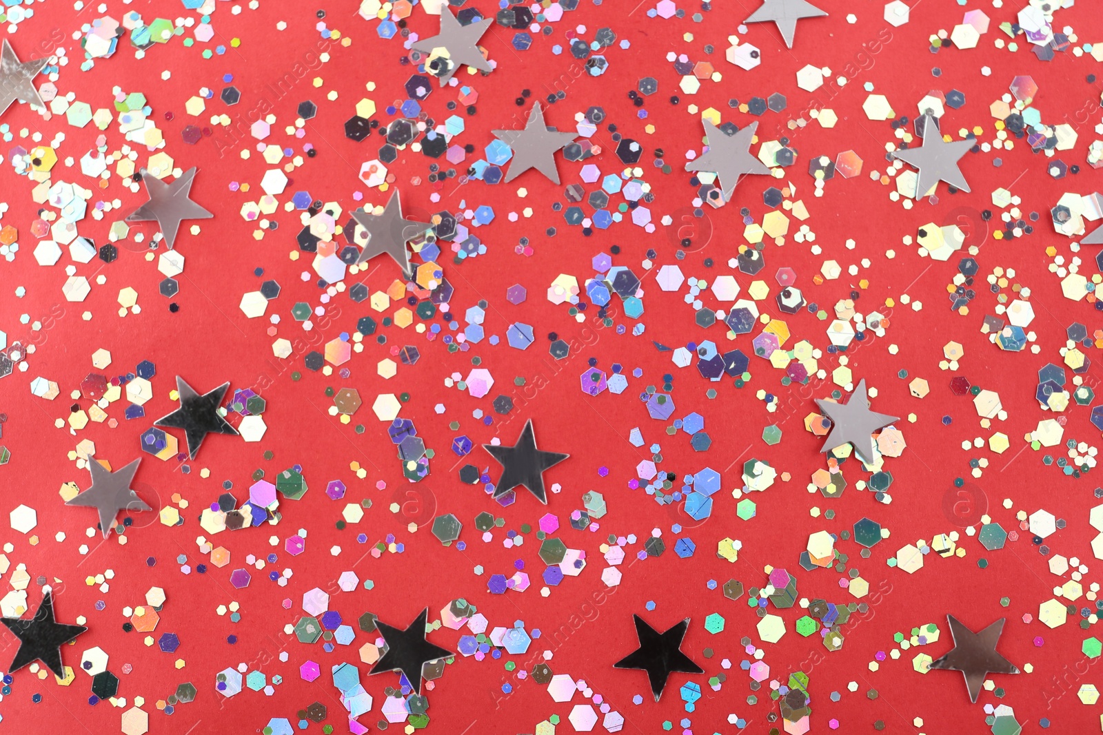 Photo of Shiny glitter on red background, flat lay