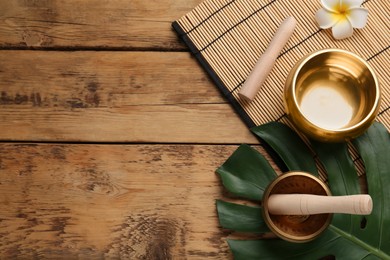 Flat lay composition with golden singing bowls on wooden table. Space for text