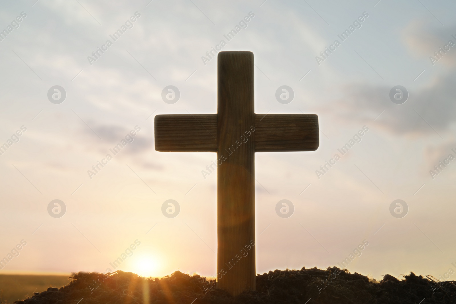 Photo of Wooden Christian cross outdoors at sunrise. Religion concept