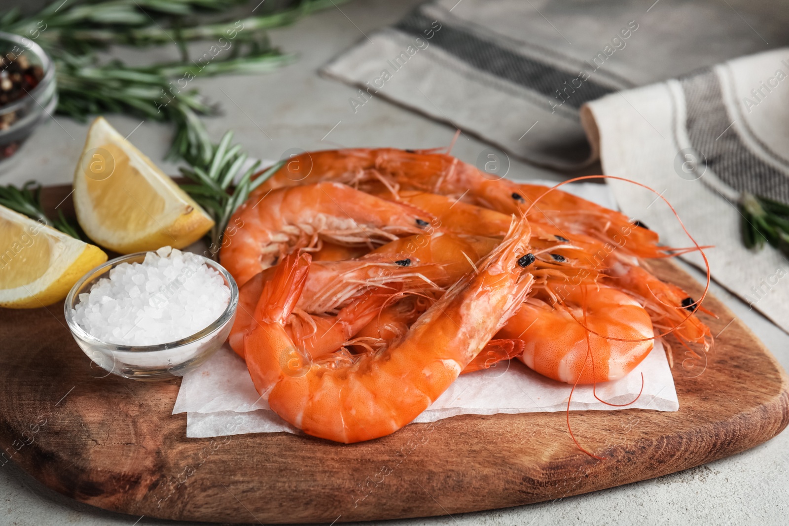 Photo of Delicious cooked shrimps, lemon and salt on wooden board