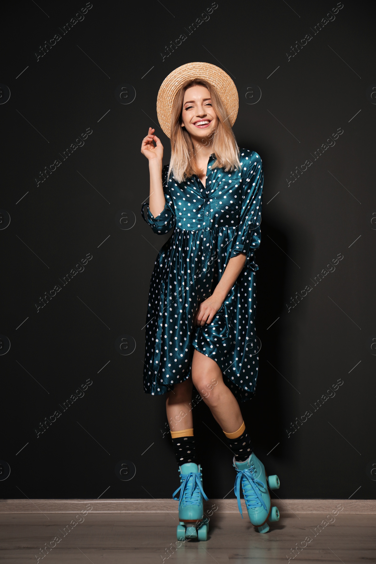 Photo of Young woman with retro roller skates against black wall