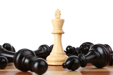 King among fallen black chess pieces on wooden board against white background