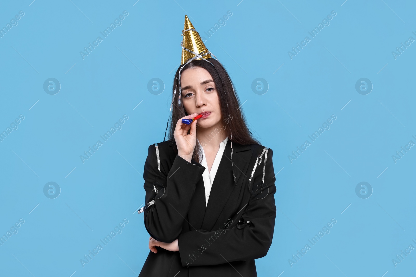 Photo of Sad woman in party hat with blower on light blue background