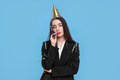 Photo of Sad woman in party hat with blower on light blue background