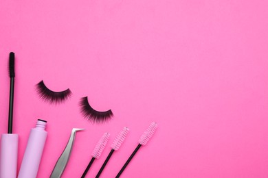 Photo of Fake eyelashes, brushes and tweezers on pink background, flat lay. Space for text