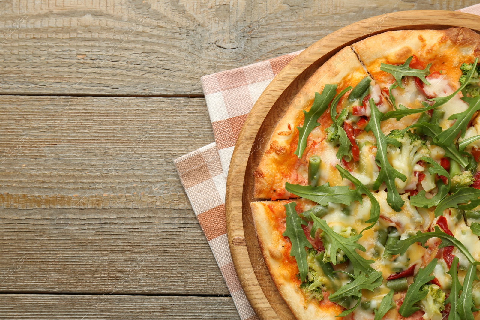 Photo of Board with delicious vegetarian pizza on wooden table, top view. Space for text