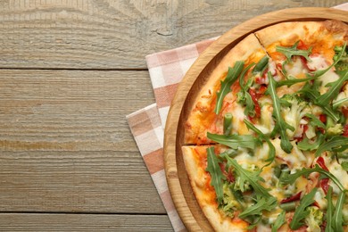 Board with delicious vegetarian pizza on wooden table, top view. Space for text