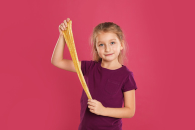 Photo of Little girl with slime on pink background