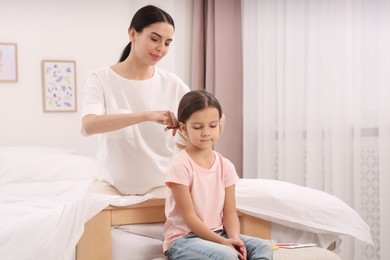 Photo of Happy woman and her daughter spending time together on bed at home. Mother's day celebration