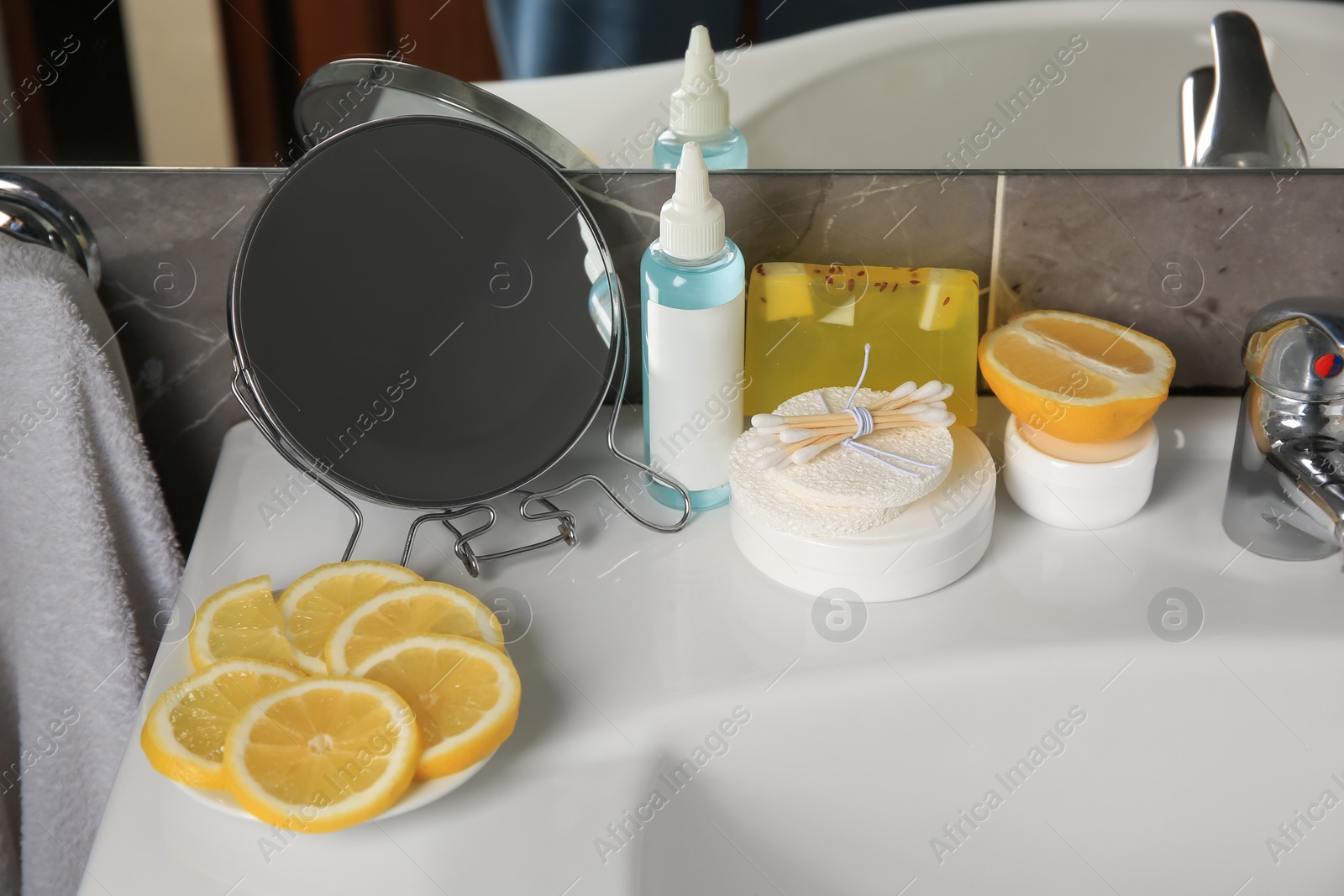 Photo of Lemon face cleanser. Fresh citrus fruits, personal care products and mirror on sink in bathroom