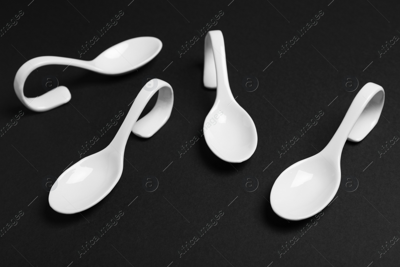 Photo of White ceramic serving spoons on black background