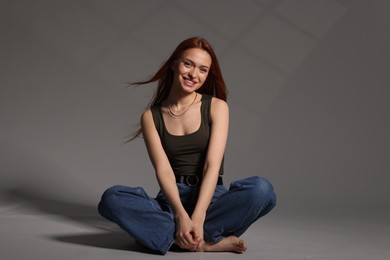 Photo of Beautiful young woman sitting on gray background