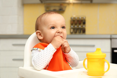 Photo of Cute little baby eating cookie at home