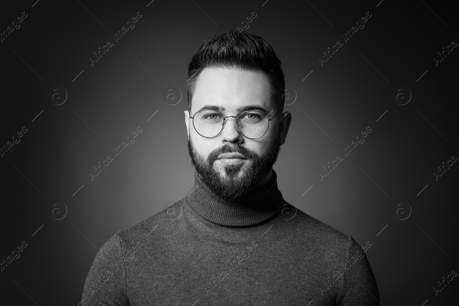 Photo of Portrait of handsome bearded man on dark background. Black and white effect