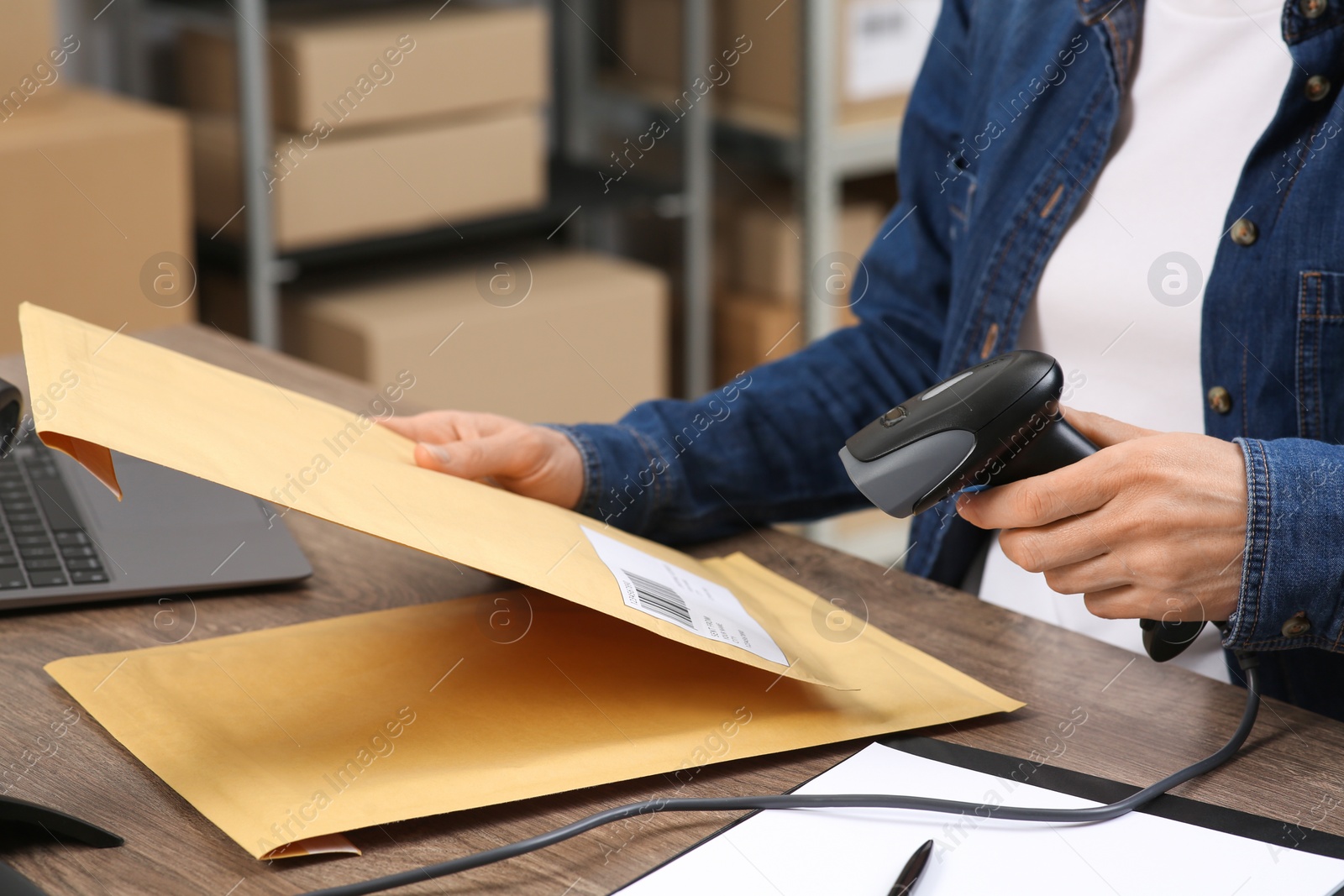 Photo of Seller with scanner reading parcel barcode in office, closeup. Online store