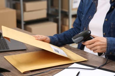 Seller with scanner reading parcel barcode in office, closeup. Online store