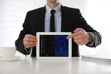 Image of Man holding modern tablet with switched on VPN at white table in office, closeup