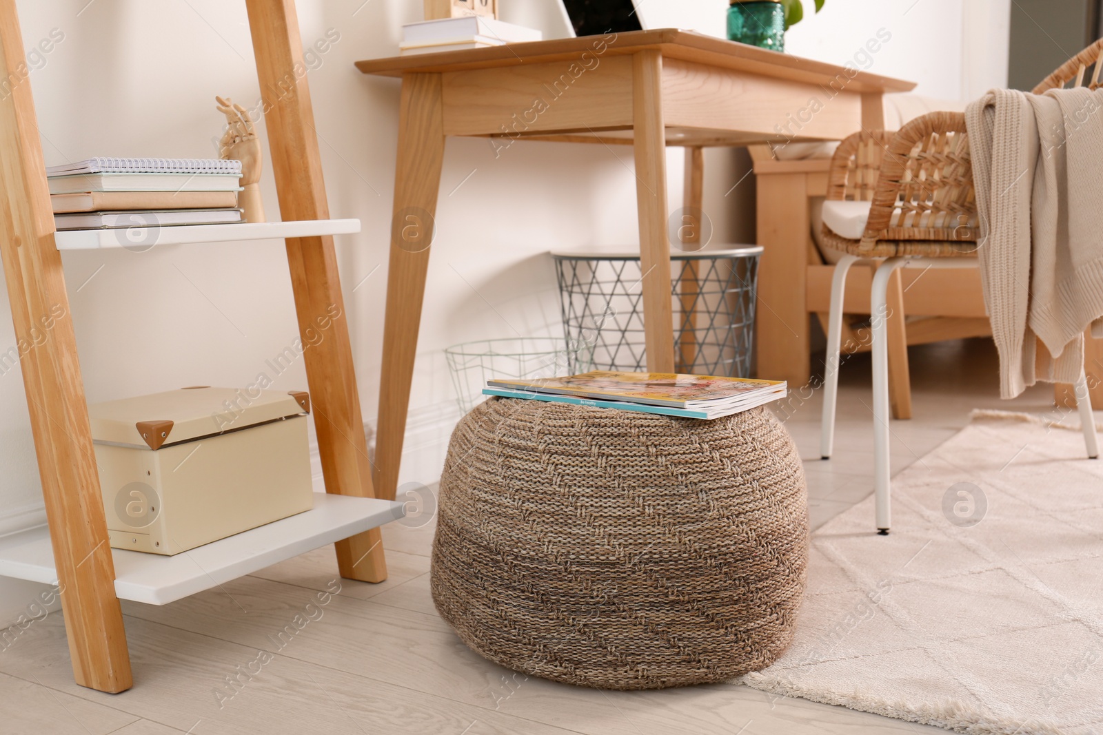 Photo of Stylish knitted pouf with magazines on floor in modern home office. Interior design