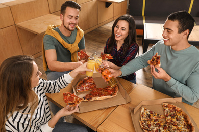 Photo of Group of friends having fun party with delicious pizza in cafe