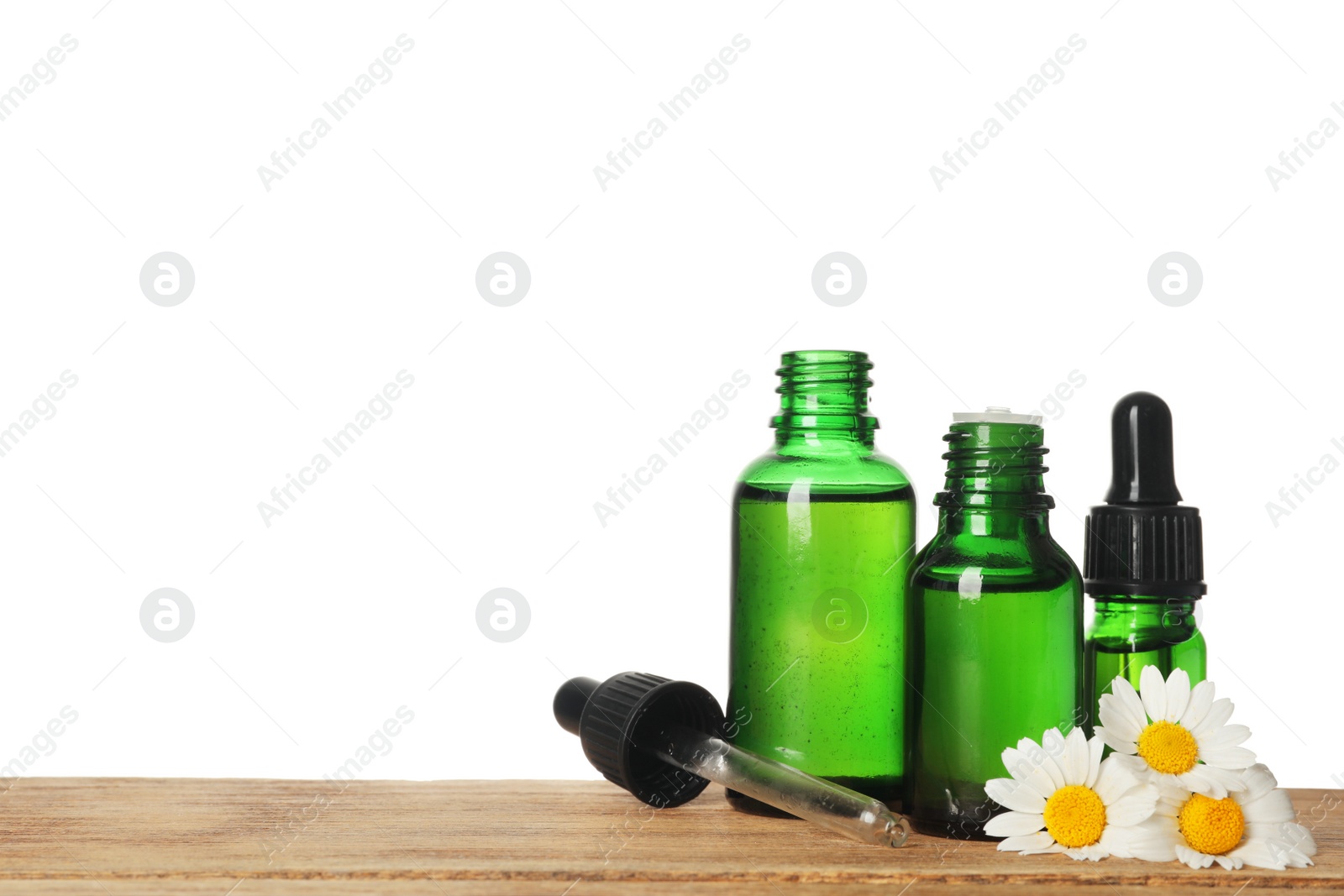 Photo of Chamomile flowers and cosmetic bottles of essential oil on wooden table against white background. Space for text