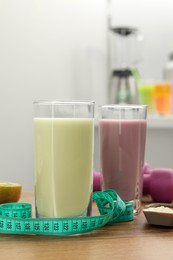 Photo of Tasty shakes, measuring tape and powder on wooden table. Weight loss