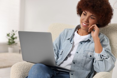 Photo of Young woman using modern laptop in room