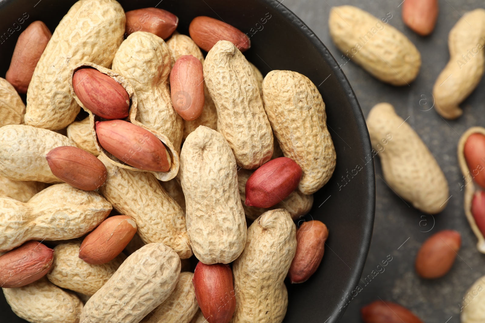 Photo of Fresh unpeeled peanuts in bowl on grey table, top view