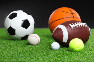 Photo of Many different sports balls on green grass against black background