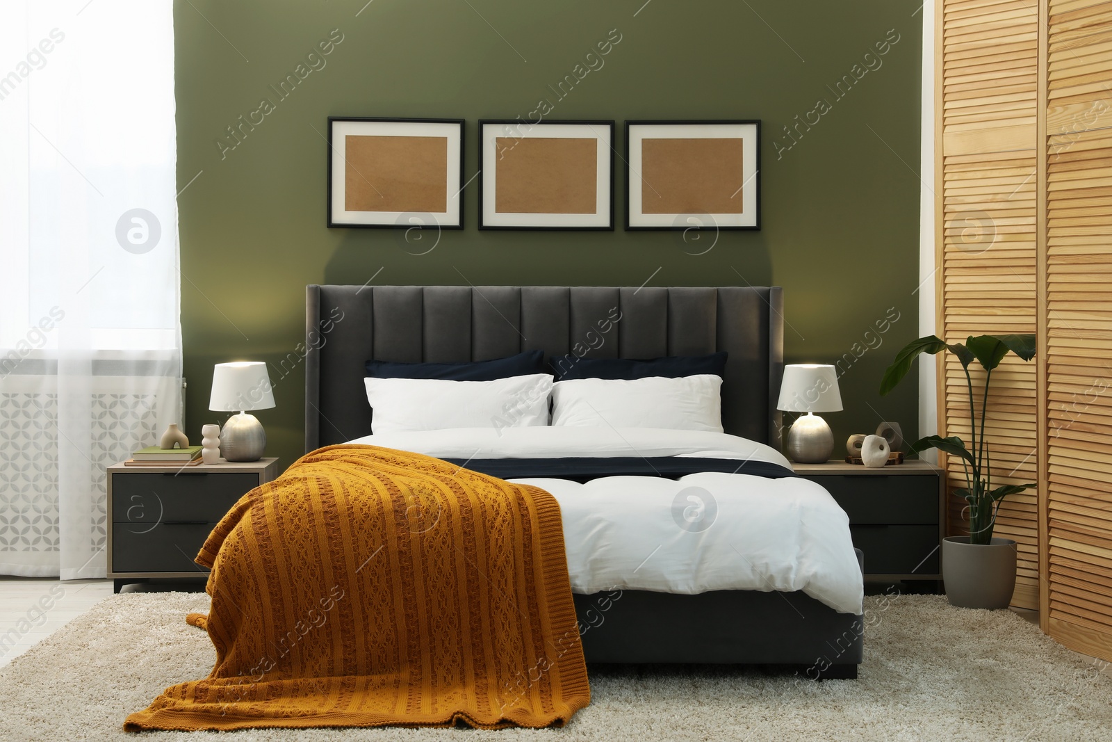 Photo of Large comfortable bed, lamps and houseplant in stylish room. Interior design