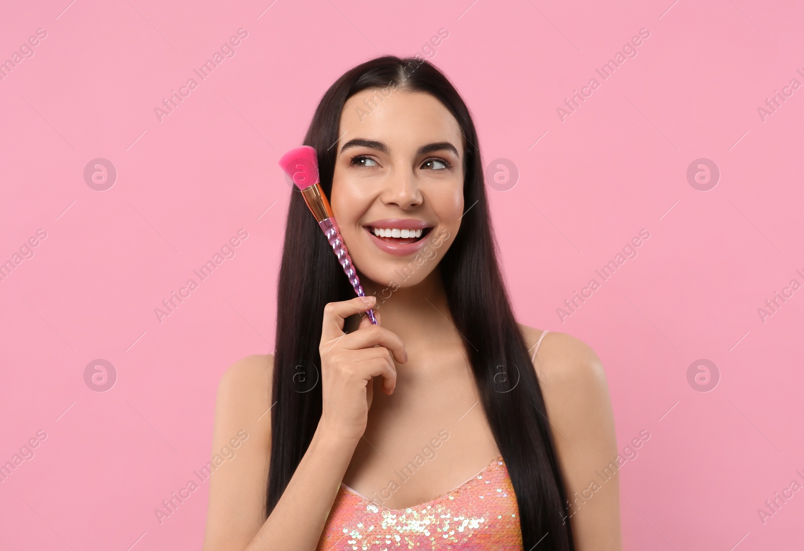 Photo of Beautiful woman with makeup brush on pink background