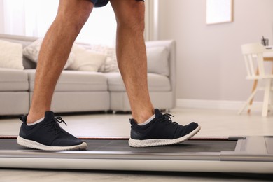 Photo of Man training on walking treadmill at home, closeup