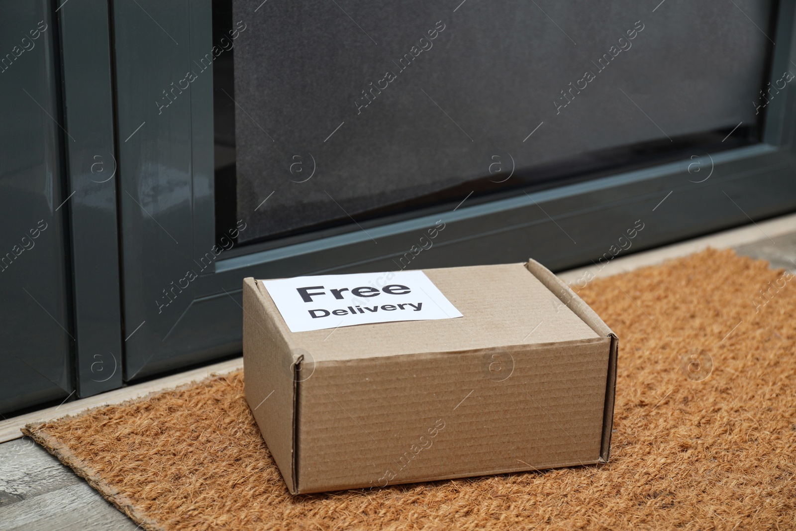 Photo of Parcel with sticker Free Delivery on rug indoors. Courier service