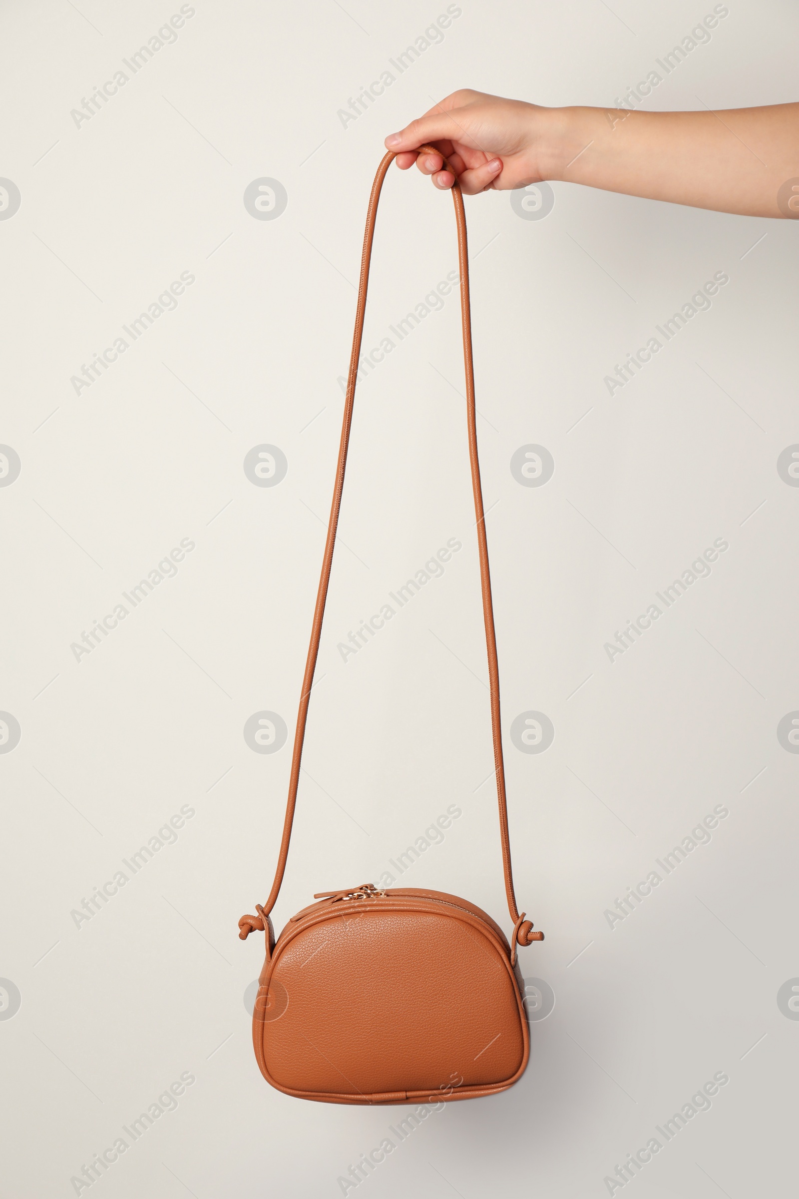 Photo of Woman holding stylish bag on light background, closeup