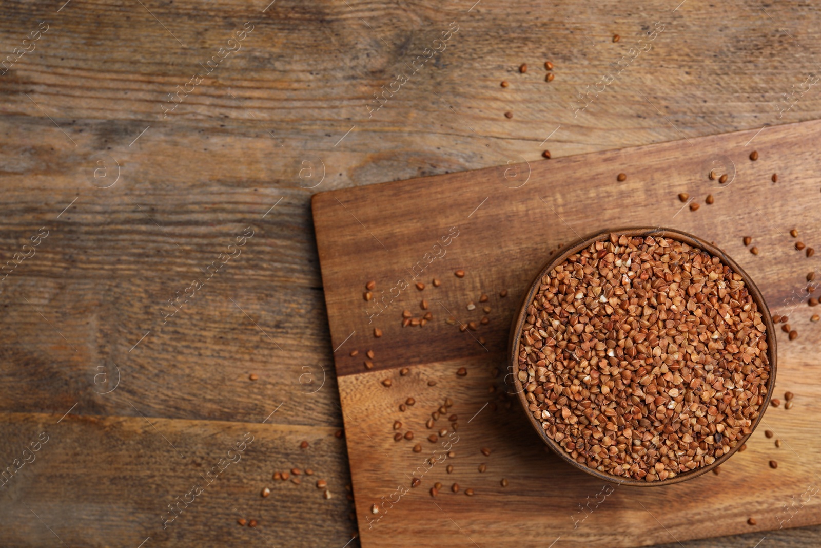 Photo of Buckwheat grains on wooden table, top view. Space for text