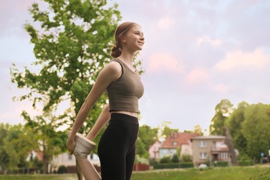 Photo of Teenage girl doing morning exercise in park, space for text