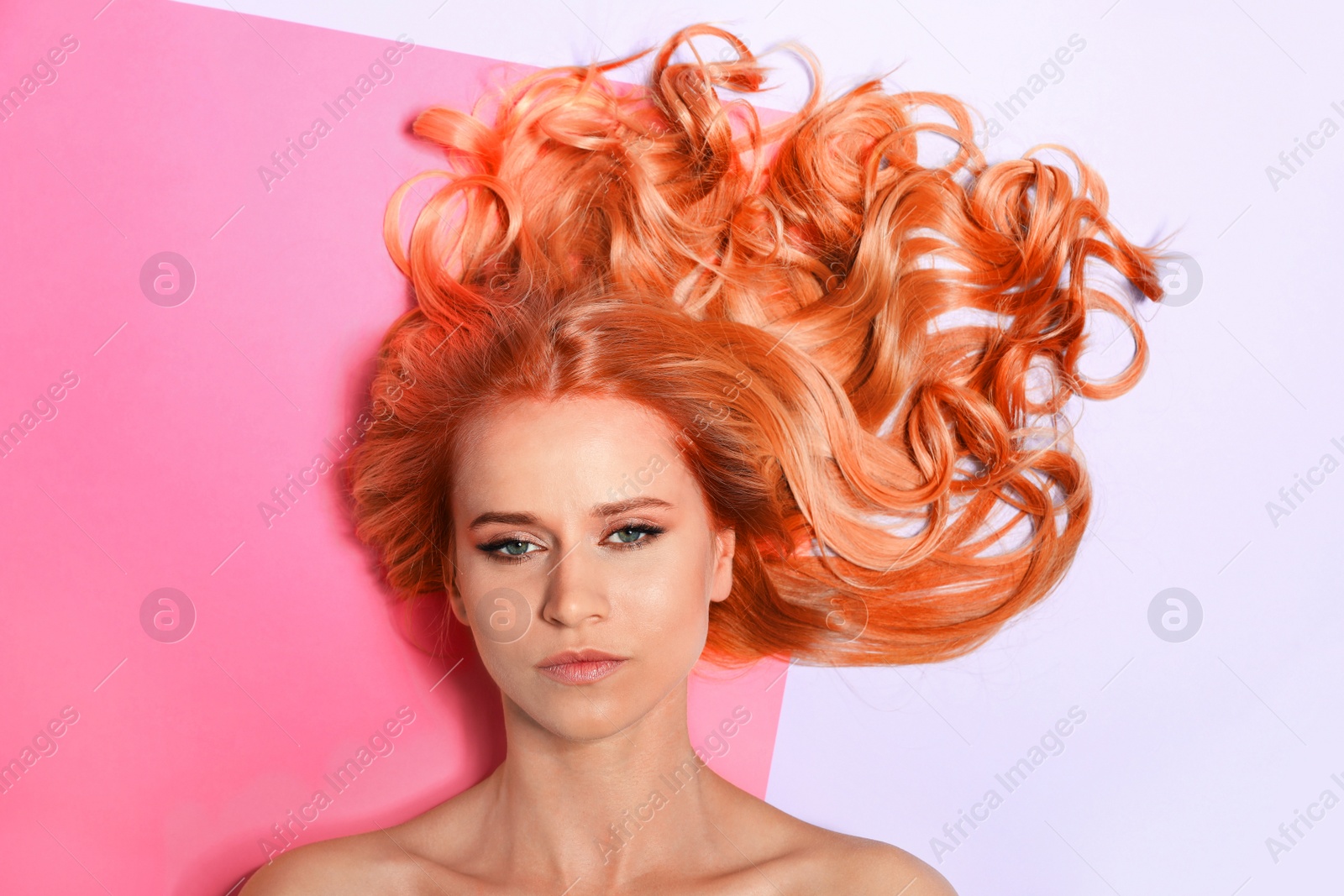 Image of Beautiful woman with long orange hair on color background, top view