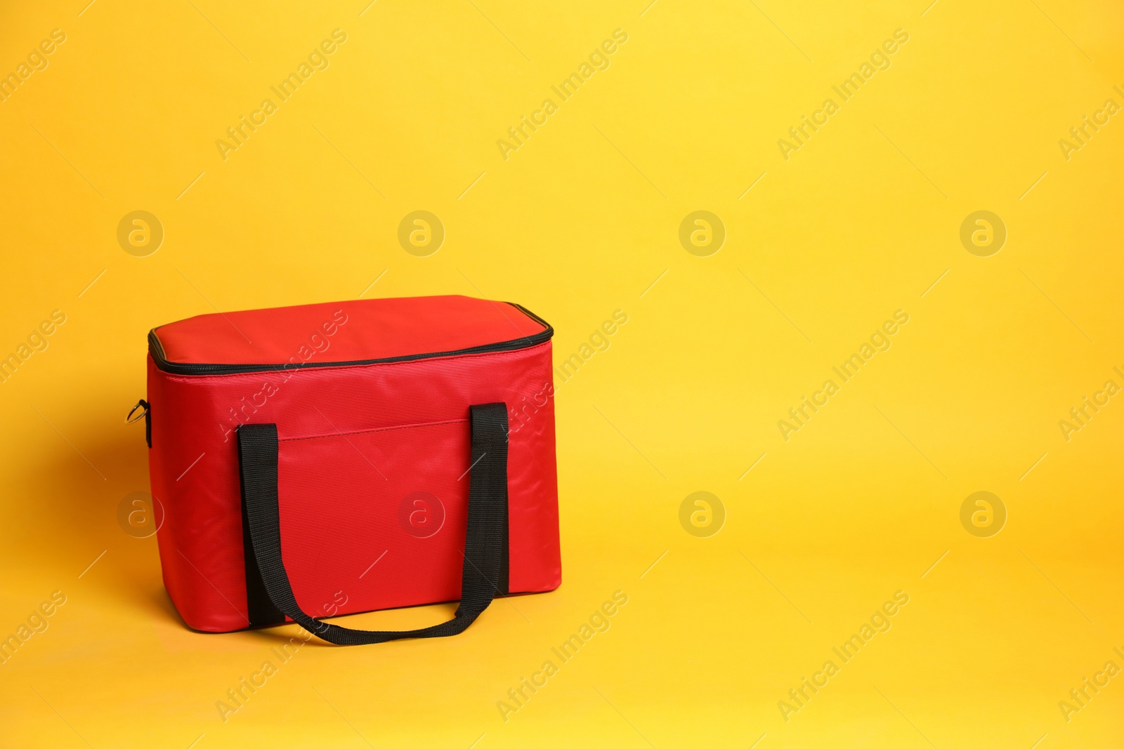 Photo of Modern red thermo bag on yellow background. Space for text