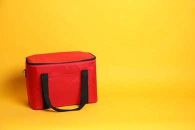 Photo of Modern red thermo bag on yellow background. Space for text