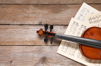 Violin and music sheets on wooden table, top view. Space for text