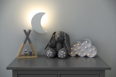 Crescent shaped night lamp above cabinet with toys