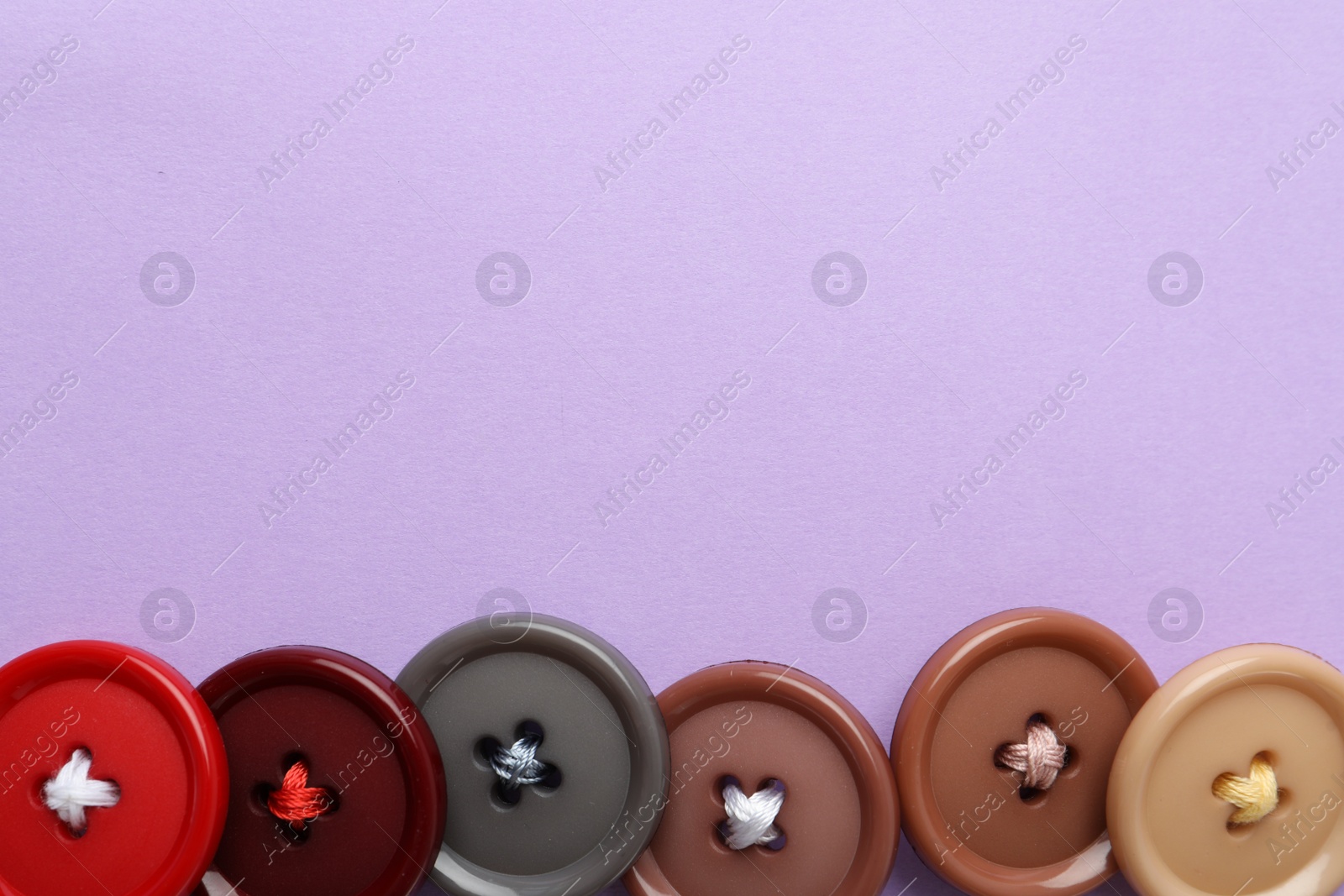 Photo of Many colorful sewing buttons on violet background, flat lay. Space for text